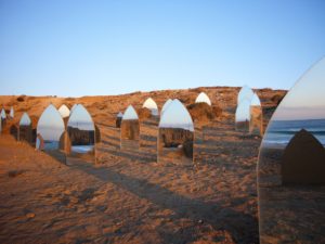 Art installation of mirrors as standing stones on the beach
